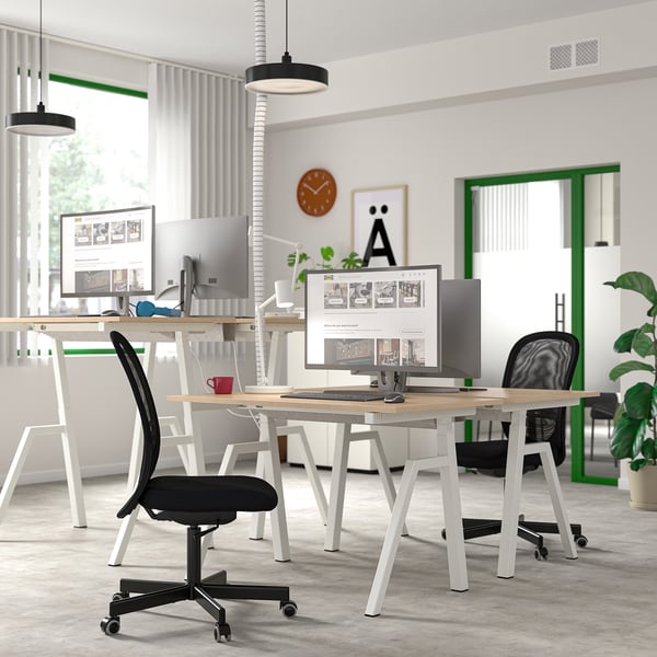 Modern TROTTEN sit/stand desks in ash and white with black/white chairs, computers, and plants in a minimalist workspace.