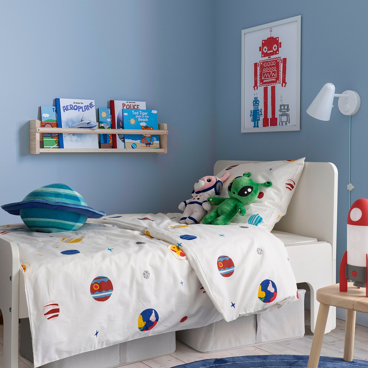 White duvet with planets, bears & alien on bed in space-themed kids room. Space-themed kids room with planets duvet, bears, & alien.