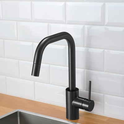 Black kitchen tap with pull-out spout, set against white brick backsplash, wooden counter, and metal sink.