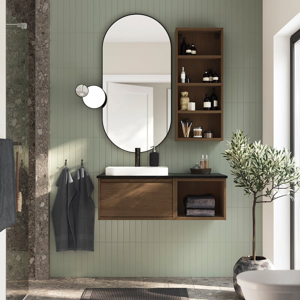 Modern bathroom with ÄNGSJÖN vanity, mirror, sink, and green tiles. Plant on right.