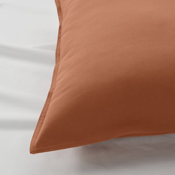 Close-up of an orange pillowcase, showcasing its soft, textured cotton fabric and neat stitching.