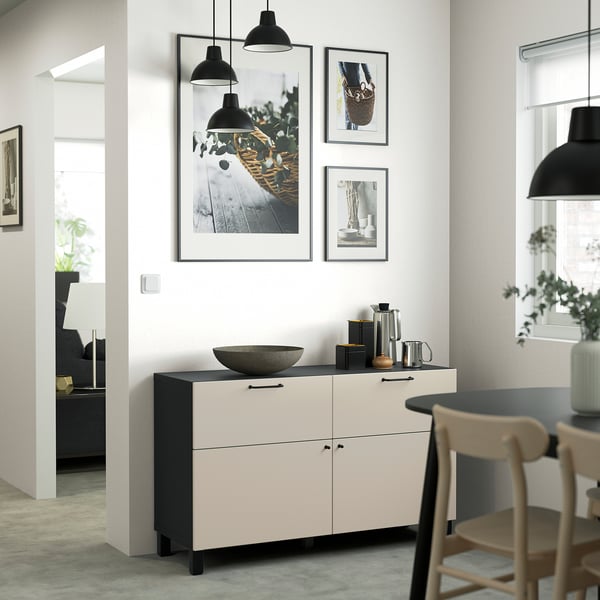 A room with a black and white BESTÅ sideboard, pendant lights, light wood chairs, and minimal decor.