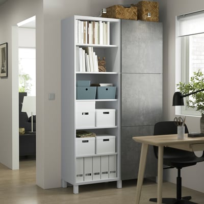 White BESTÅ storage unit in home office with mixed open/closed shelves, nearby desk and chair. Bright room with wooden floor.
