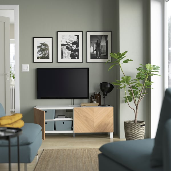 Modern living room with BESTÅ tv unit, flat-screen tv, blue chairs, and decor.
