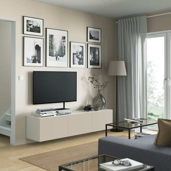 Modern living room with BESTÅ white tv bench, black tv, styled decor, black-and-white framed photos, and large window with grey curtains.
