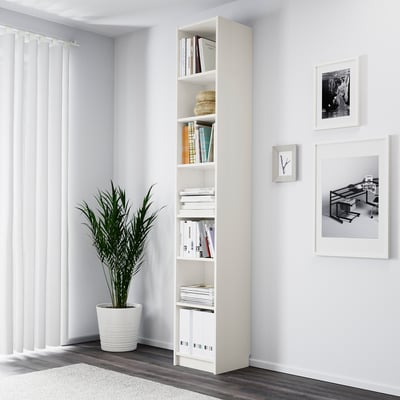 Minimalist room with BILLY white bookcase, tall plant, and wall art.