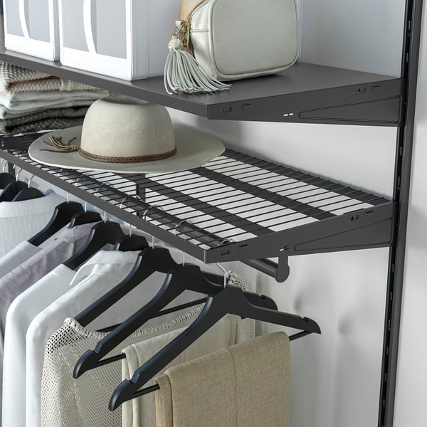 Closet with dark shelves holding clothes, a hat, and a bag. Clothes hang below.