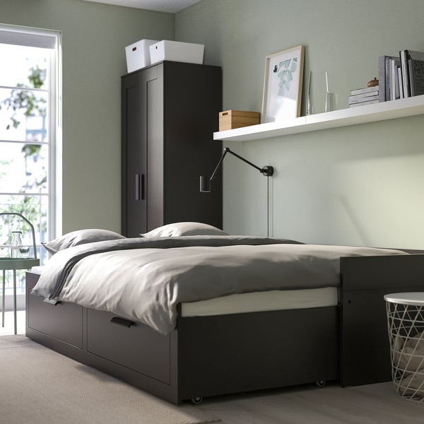 Modern bedroom with grey BRIMNES day-bed, transforming into double bed with large drawers for storage. Tall wardrobe and wall shelves.