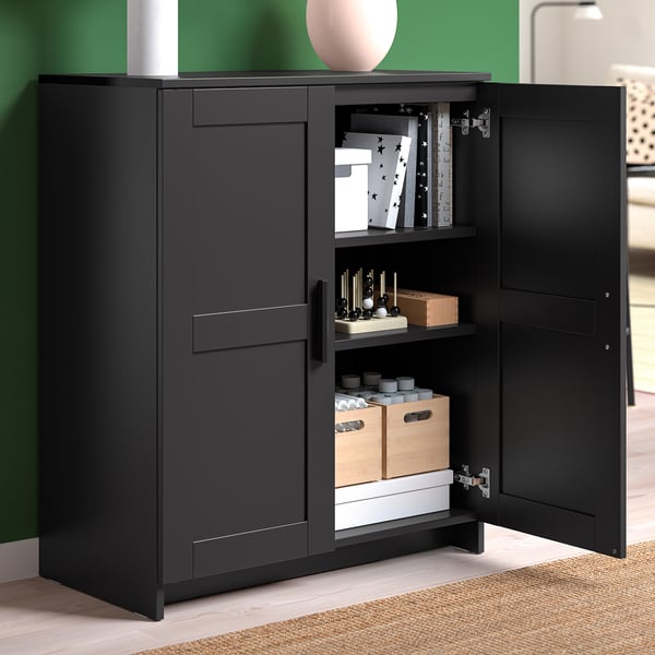 Black tv cabinet with open doors revealing storage shelves and cable outlets.