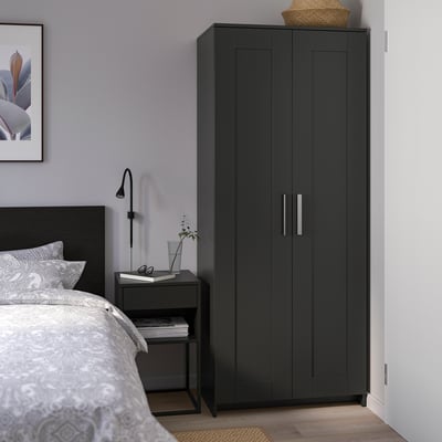 Modern black BRIMNES wardrobe between ikea bed & side table, stylish & practical storage.
