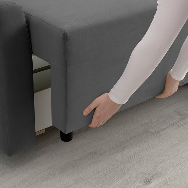 Person adjusting grey sofa bed with storage underneath, showcasing its transformable and organised design.