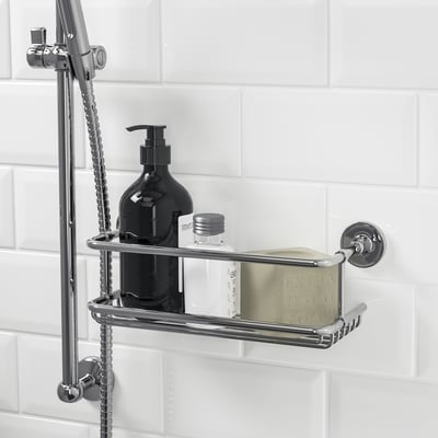 Shower shelf with chrome details holds toiletries. Keeps items tidy and handy.