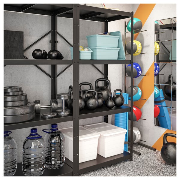 Home gym black BROR shelving system storing water bottles, kettlebells, and plastic containers. Gear organised neatly against grey wall.
