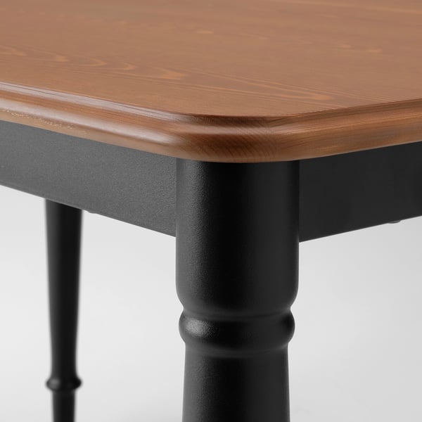 Wooden table closeup: smooth, polished top, strong matte black legs.