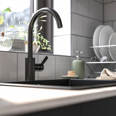 Modern black kitchen tap with high arc spout, sleek design, positioned near sink, surrounded by plates and soap dispenser.
