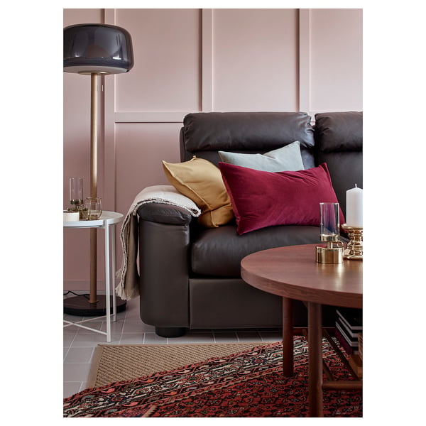 Modern living room with dark grey leather sofa, colourful pillows, wooden coffee table, and stylish floor lamp.