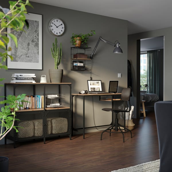 Modern home office with FJÄLLBO shelf, desk, and chair. Dark wood floor, grey walls, plants, and clock. Industrial and rustic design.