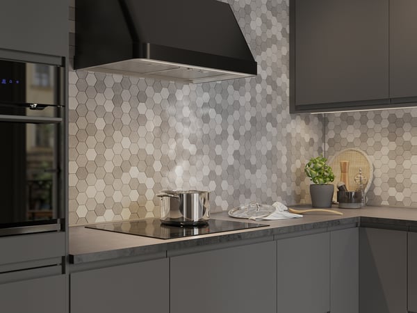 Modern kitchen with black cabinets, range hood, stove, tile backsplash, lights, plants.