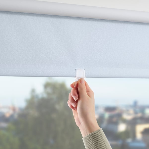 Person adjusting a roller blind, blocking light; cordless for safety.