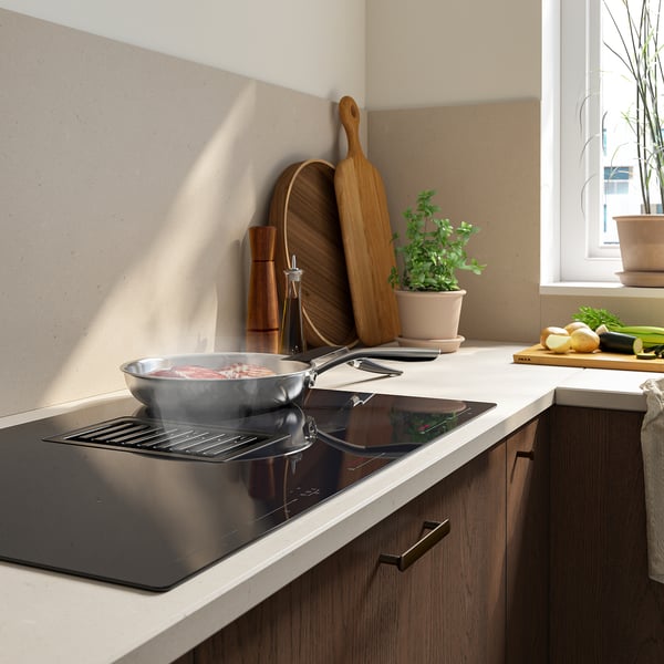 Modern kitchen with a sleek, black induction hob featuring integrated extractor hood and a skillet.