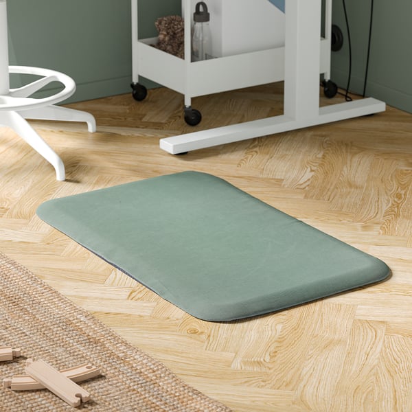 Green FREIVID standing mat on wood floor by white desk and chair.