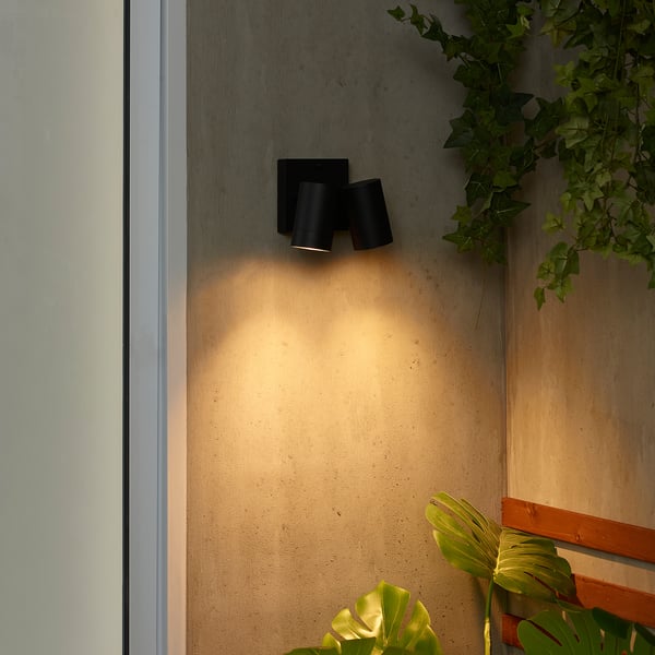 Black wall lamp with 2 bulbs, green plants, adds cozy light.