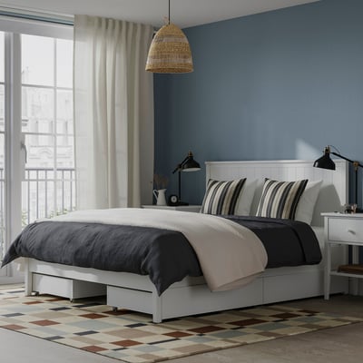 Modern bedroom with white GULLABERG bed. Large, blue walls, striped pillows, black lamp. Rug under, curtains to side.