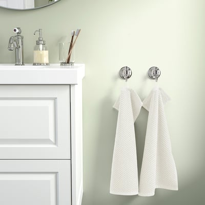 Beige GULVIAL towels hang on hooks by white vanity with mirror.