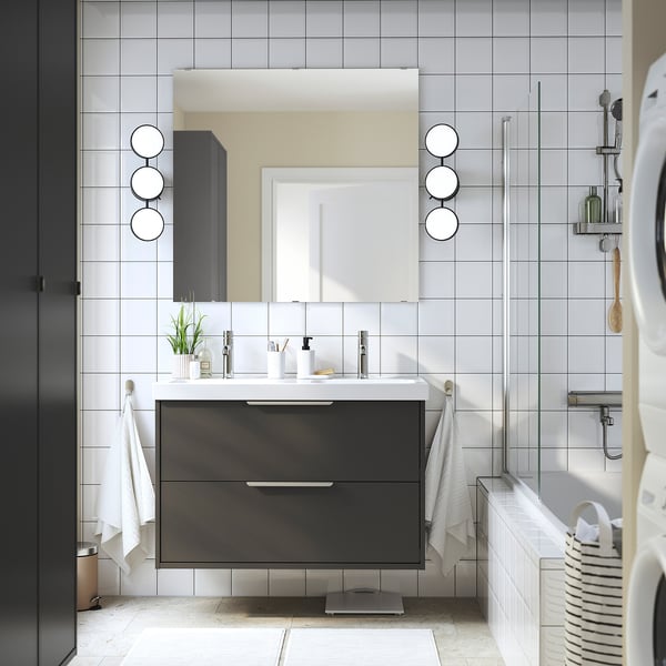 Modern bathroom with dark grey HAVBÄCK vanity, double basin, round mirrors.