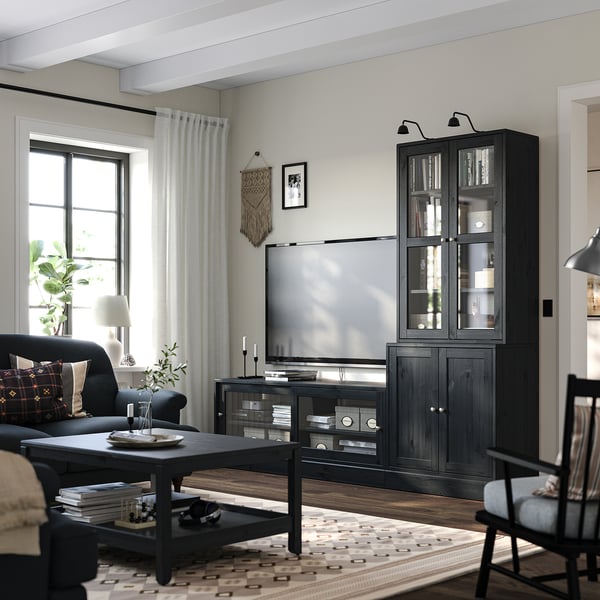 Modern living room with dark wood HAVSTA furniture, flat-screen tv, couch, coffee table, books, and plants.