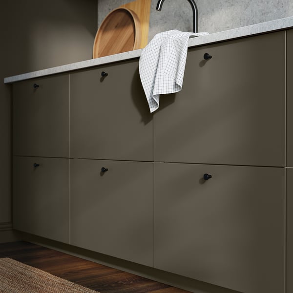 Modern kitchen cabinets in dark brown with sleek black handles. A white towel hangs from a hook. Wood tray on top.