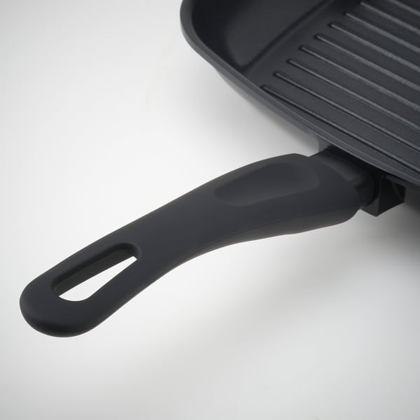 Black grill pan with ergonomic handle on white surface. Non-stick, even heat, easy handling.
