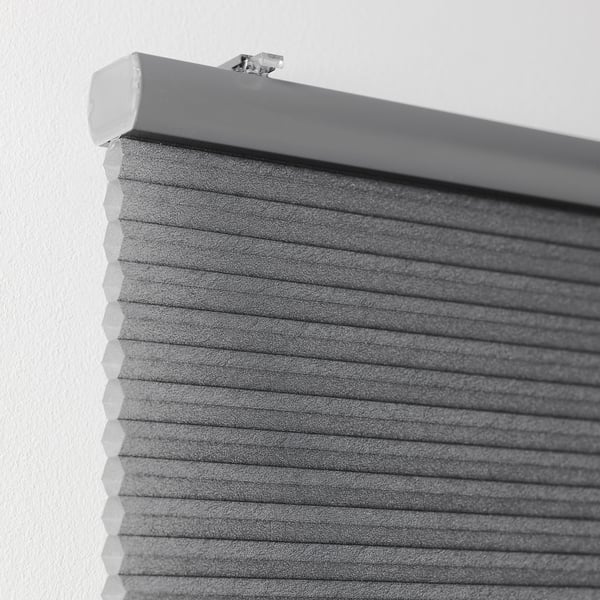 Close-up of a grey cellular blind mounted on a wall, showing its texture and hidden cord for safety.