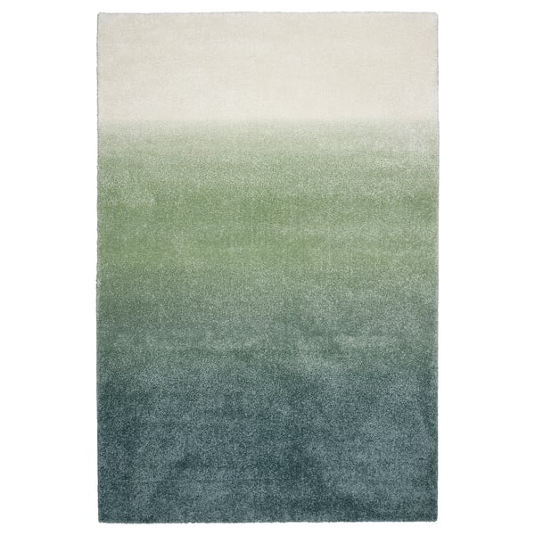 The HOTELLRUM rug with a gradient of blue, green, and white shades, rectangular shape, and soft texture.