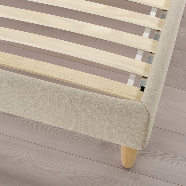 Light wooden bed with beige upholstery, featuring slatted design and sturdy wooden legs.