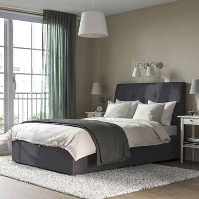 Modern bedroom with IDANÄS ottoman bed, white bedding, nightstands, lamps, clock, and green walls.