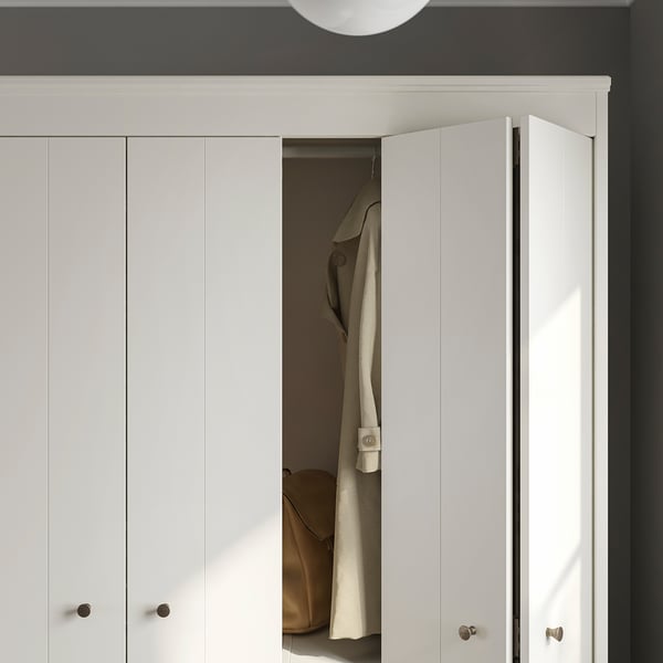 White wardrobe with bifolding doors, partially open, revealing hanging jacket. Modern, clean design.