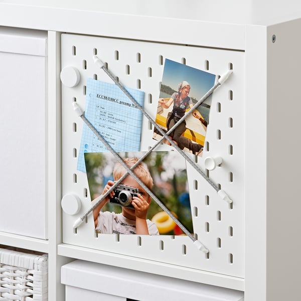 White KALLAX shelf with pegboard door, displaying photos and notes, for personalised storage and organisation.
