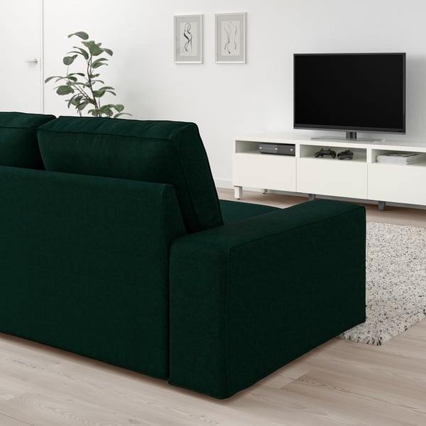 Modern living room with large green KIVIK sofa, white tv stand, and wall art.