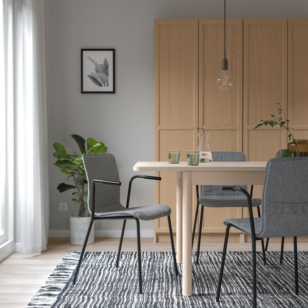 Modern dining set with wooden cabinet, table, grey LÄKTARE chairs, bulb light, plant, and patterned rug.