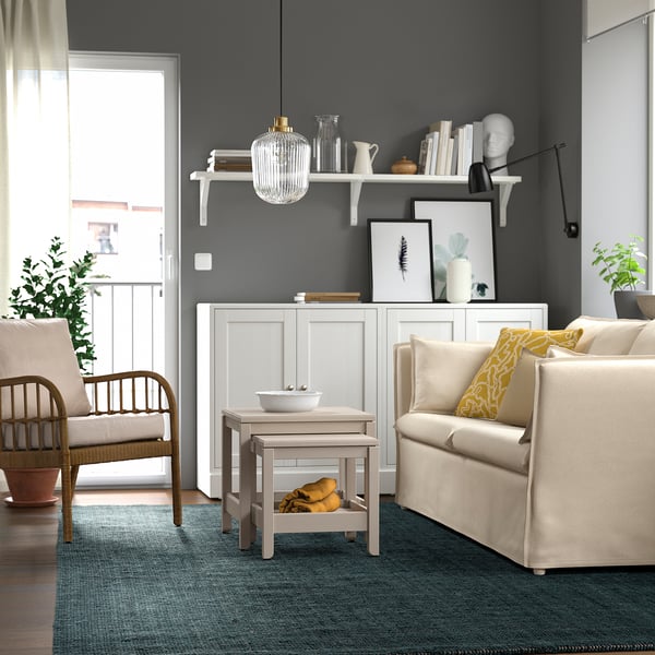 Modern living room with LANDBANA jute rug, two armchairs, sofa, and decor on grey wall shelves, creating a cosy atmosphere.