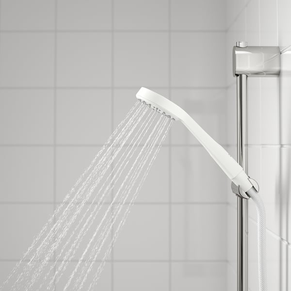 Hand shower in use, wide spray vs. Tiled wall, chrome holder attached.