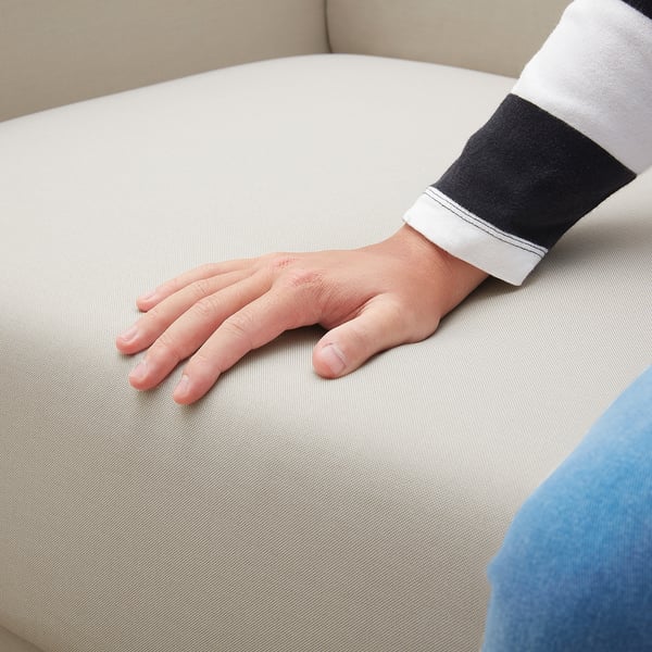 A hand rests on a light grey LINANÄS sofa, wearing a black and white striped sleeve.