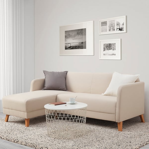 Modern tan sofa, grey pillows, white coffee table, framed art, large window.