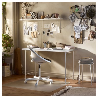 Bright, modern workspace featuring a white lindom table with adjustable chair, surrounded by books, art, and decorative items.