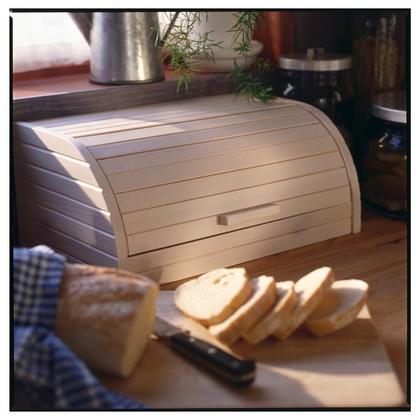 Wooden light beige bread box with sliced bread and knife on table.