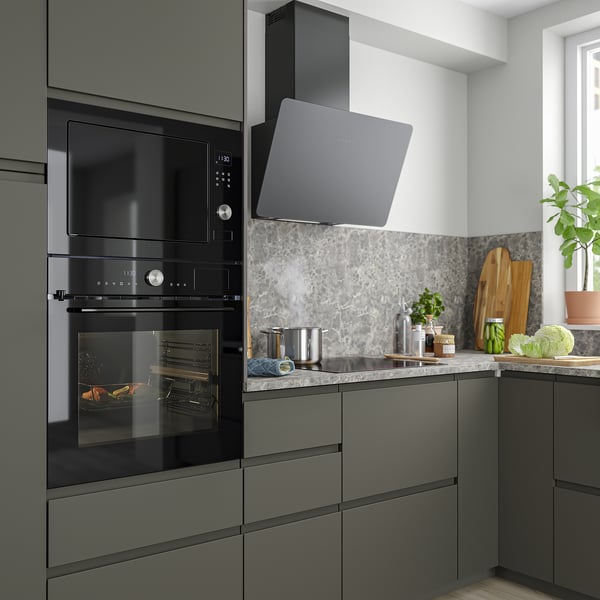 Modern kitchen with black MÅGEBO microwave and oven, dark cabinets, gray marble, and plants.
