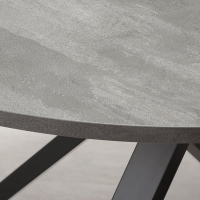 Close-up of modern table edge. Grey tabletop with smooth, bevelled edge supported by angled metal legs.