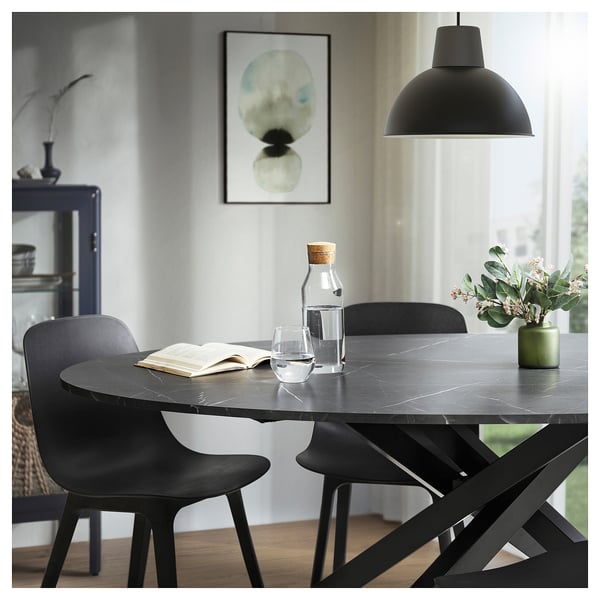 Modern black dining set with oval table, four chairs, and pendant lamp.