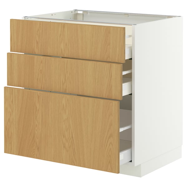 A white METOD kitchen cabinet with three oak drawers. The drawers are partially open, revealing storage compartments.